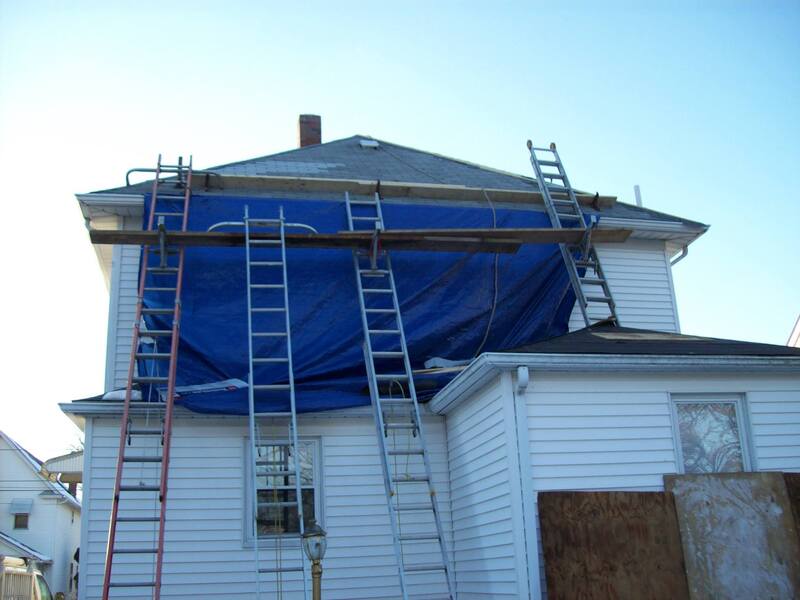 four ladders leaning on house with scaffolding for roofing project